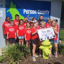 group of children standing in front of Animal Services sign holding a sign that says "You are Pawsome"