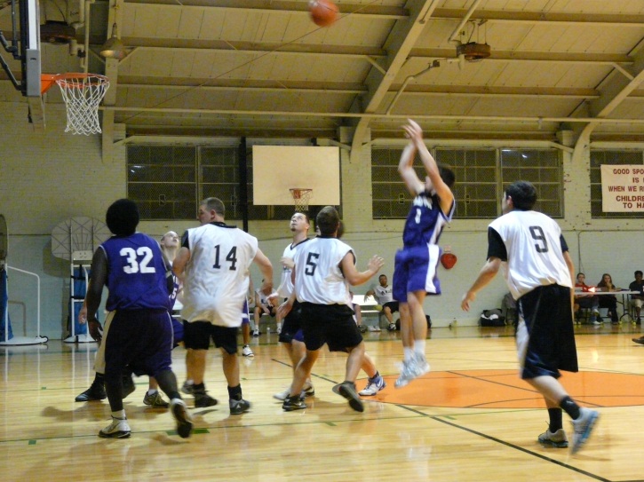 Basketball players playing game, one shooting